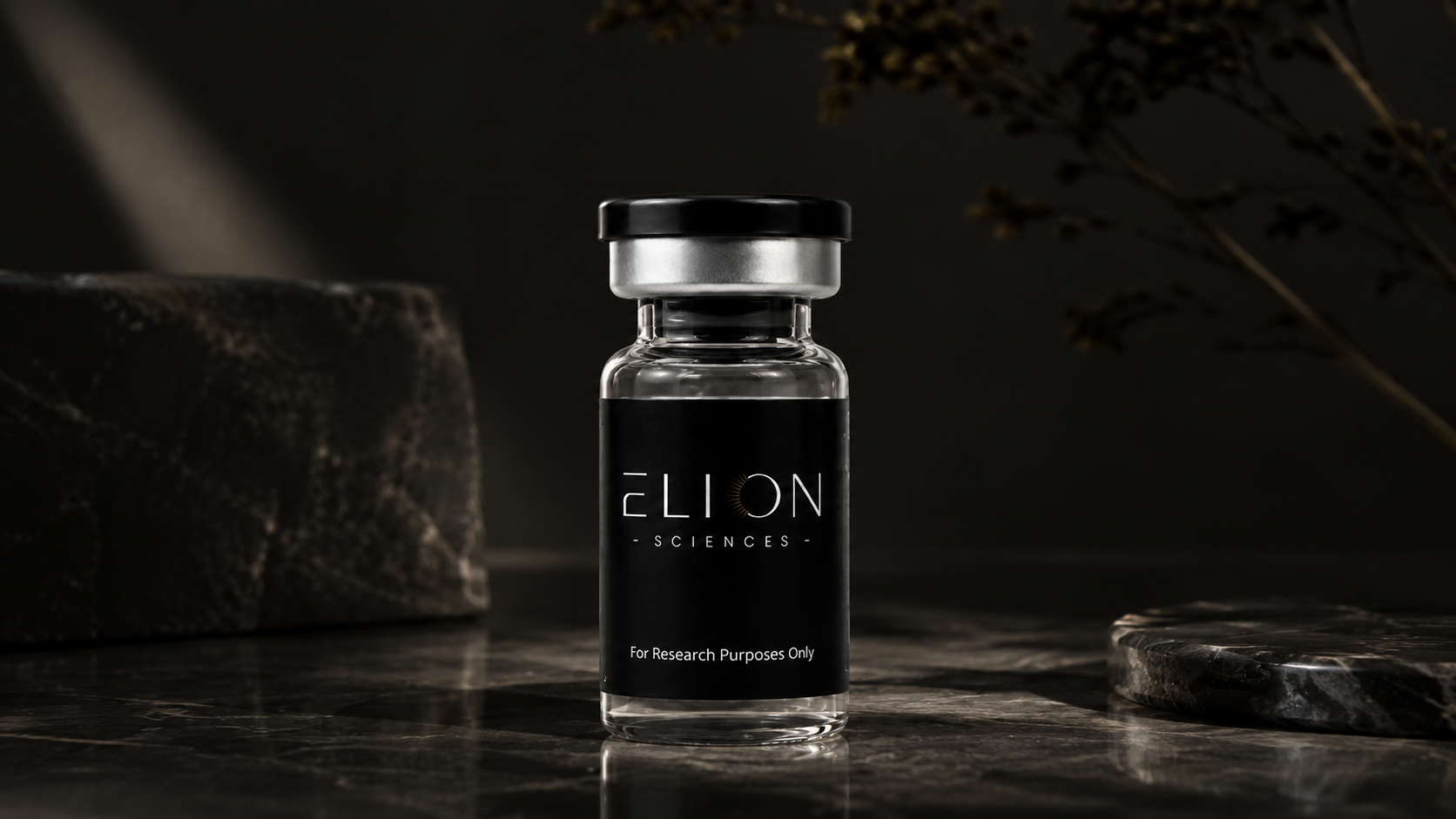 Clear glass Elion Sciences research vial with a black label and silver-and-black cap, displayed on a reflective black marble surface with dramatic soft lighting, dark stone accents, and blurred botanical elements in the background.