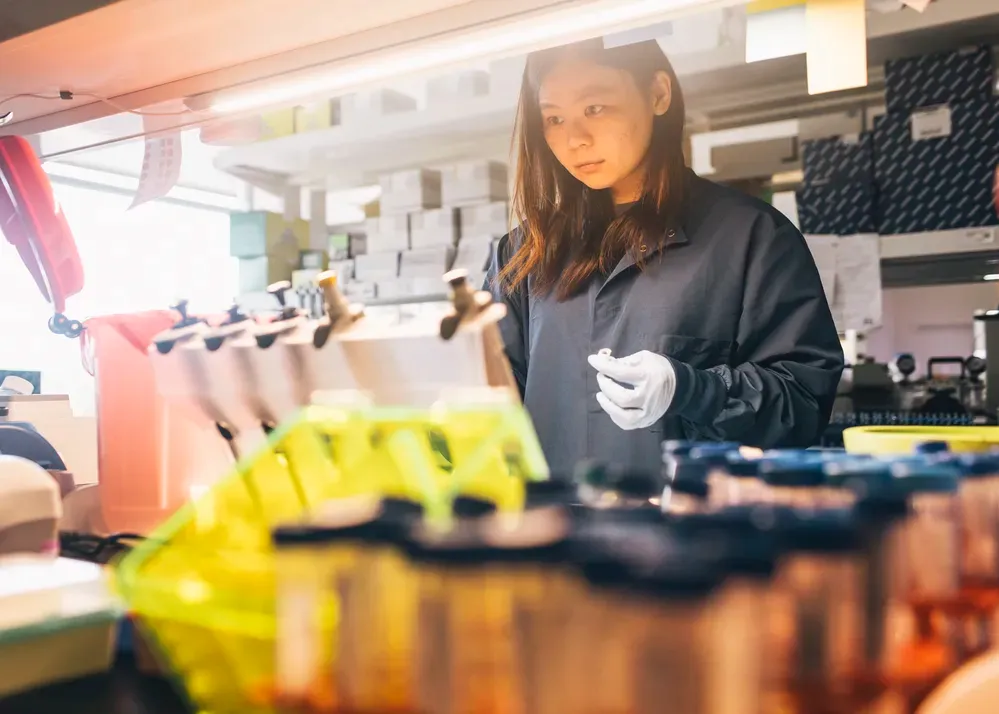 A researcher working inside a specialized laboratory facility equipped with testing apparatus and sample containers.