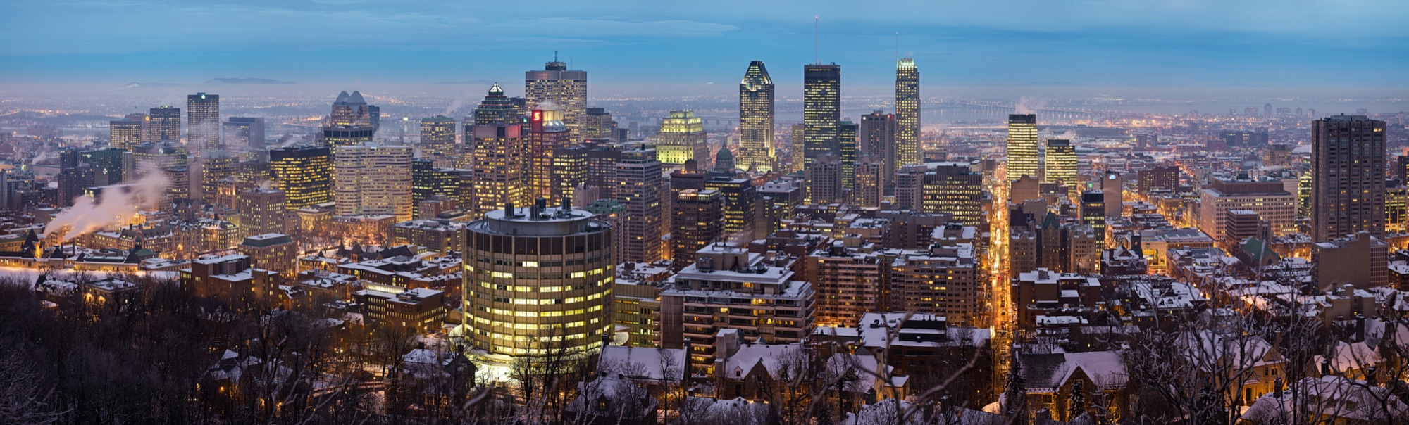 Montreal's downtown skyline at winter twilight, snow on the rooftops, seen from Mount Royal